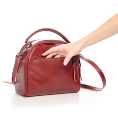 Woman's female red leather bag in hand pulls out of the bag on white background isolation