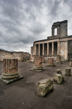 ruins of columns and temple under fark clouds in Pompei in Italy