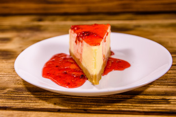 White plate with cheesecake New York and raspberry jam on wooden table
