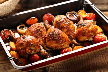 Roasted chicken drumstick with potatoes and salad on wooden background