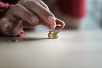 Closeup of male senior hands stacking Euro coins