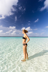 junge Frau im Bikini steht im klaren Wasser auf den Malediven
