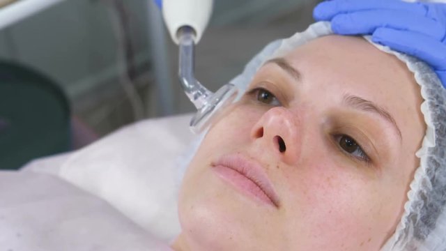 Beauty treatment facial electric darsonval therapy at cosmetology clinic.
