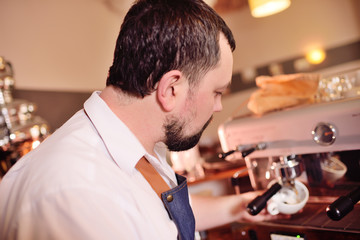 a handsome, bearded barista man holding a Holder with ground coffee. Making coffee in a coffee house