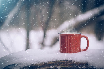 Mulled wine in a red cup. Hot winter drink outdoor in snowy winter forest in cold weather....