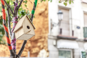 Bird house hanging from the branch of a small tree