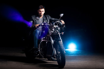 Naklejka na ściany i meble Cute biker in leather jacket sits on a motorcycle in blue smoke 