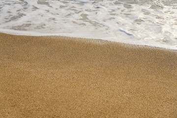 Fototapeta na wymiar Waves with foam hitting sand on the beach texture. 
