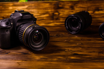 Modern dslr camera and lenses on wooden table