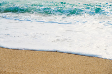                      Waves with foam hitting sand on the beach texture.          