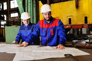 Two workers in construction helmets discuss a plan, blueprint or industrial project in the...