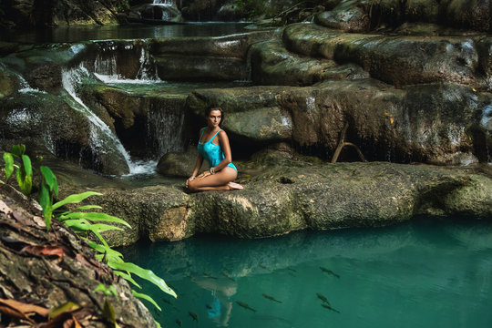Young and sexy woman on the beautiful waterfall in the jungle