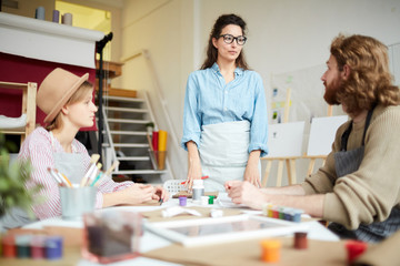 Obraz premium Young coach looking at one of students at seminar during their conversation