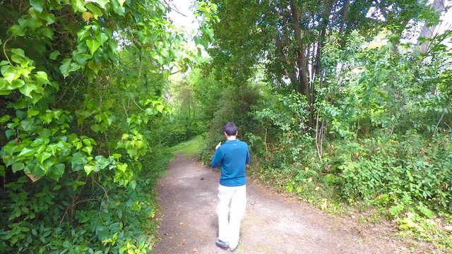 Man Shooting A Video On A Forest Path With His Smartphone
