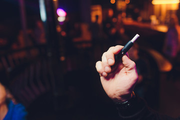 A heat-not-burn tobacco product technology.Man holding in one hand smoking module before smoking.