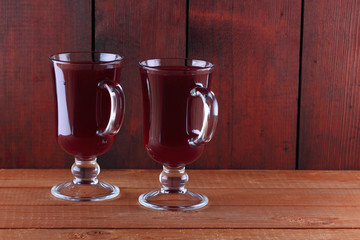 Mulled wine on wooden boards. Christmas mulled wine in glass cups. Alcoholic drink of wine and fruit. Festive drink on wooden boards. Copy space