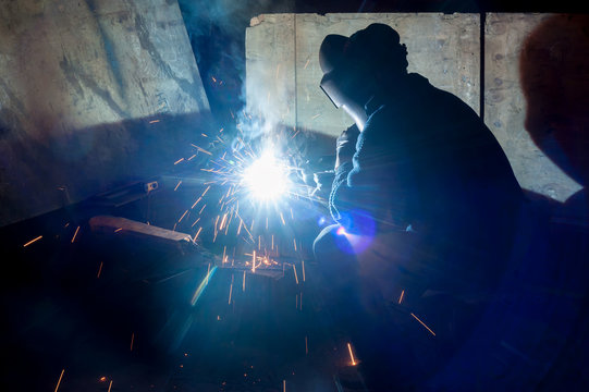 welder with protective mask welding metal and sparks