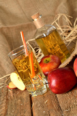 Apple juice with ice, red apples, straw, still life on a wooden table vertical photo