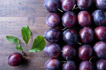 Ripe juicy plums on a wooden background.