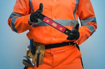 The builder holds in hands a construction water level close up isolated on blue background.