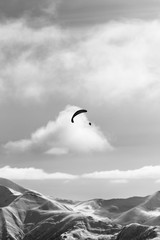 Silhouette of paraglider in winter snowy mountains at nice sun evening