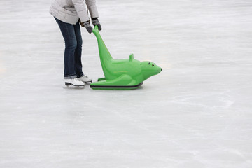 Skater helpers to keeps balance on ice. Woman on the figure skates with learning figure outdoor on...