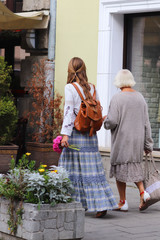 Lviv, Ukraine - 9 9 2018: A girl with long, loose hair walks in beautiful hippie style clothes along the ancient streets of a medieval city with elders woman. Two tourist in fashionable stylish clothe