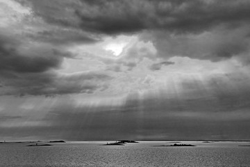 The sun behind the clouds with rays of light shining down on sea