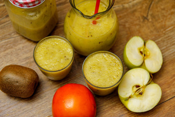 Freshly blended fruit smoothie with fresh fruits on wooden table with raw fruits