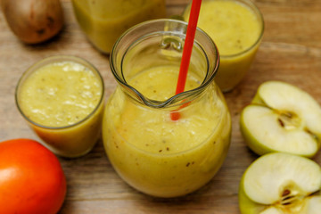 Freshly blended fruit smoothie with fresh fruits on wooden table with raw fruits