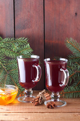 Mulled wine and Christmas tree branches on wooden boards. Christmas mulled wine, cinnamon sticks, anise and honey. Alcoholic drink of wine, fruit and honey. Festive drink on wooden boards