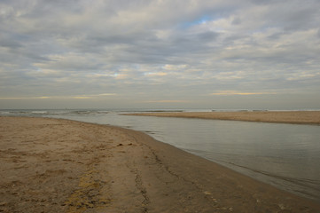 Nadmorskie wybrzeże, plaża i morze pod niebieskim niebem z chmurami.