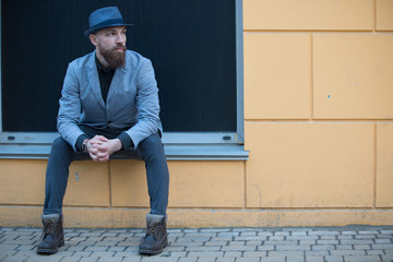 stylish man with a beard and a hat near the desirable wall