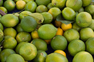 soft focus green lemon fruits background texture on open air market counter
