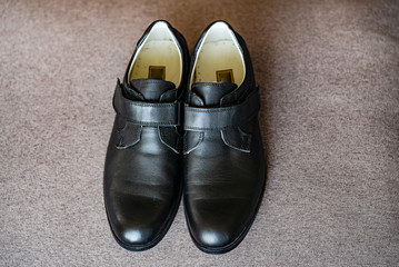 A pair of smart children's shoes standing together. Black leather boys school shoes isolated on a plain background. Close-up