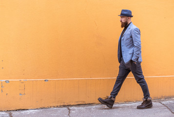 stylish man with a beard and a hat near the desirable wall