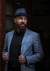 stylish man with a beard in a hat on the street
