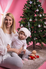 Mother and baby daughter by the Christmas tree