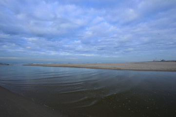 Nadmorskie wybrzeże, plaża i morze pod niebieskim niebem z chmurami.