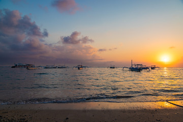 Beautiful sunrise at Sanur Beach, Bali. Traditional fishing boat on seashore at colorful sunrise. Indonesia.