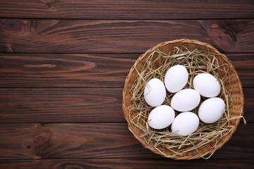 Fresh Chicken eggs in basket on brown wooden background