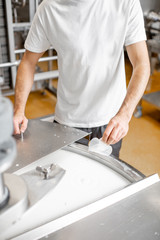 Worker adding supplements during the milk fermentation process in the stainless tank at the cheese...