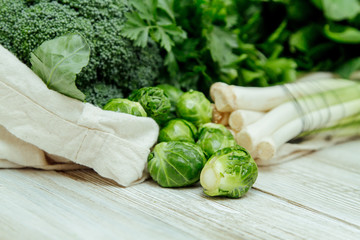 Broccoli, brussels sprouts, leek and parsley in the canvas reusable bag on the wooden table. Less...