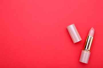 Nude lipstick on red background, close up