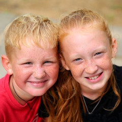 Portrait of two happy pretty redhead girl and boy with blue eyes in sunny day in park. Cute brother and sister with freckles © AnnKot