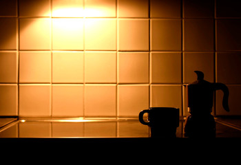 Italian coffee machine and coffee cup in low light kitchen