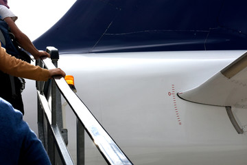 people boarding a plane holding the handrail