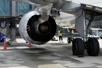 Airplane inspection prior to departure with plane turbine in the foreground 