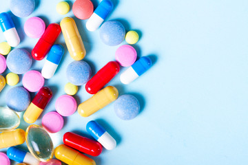 Pile of medical pills on blue background with copy space
