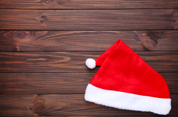 Obraz na płótnie Canvas Santa Claus red hat on brown wooden background